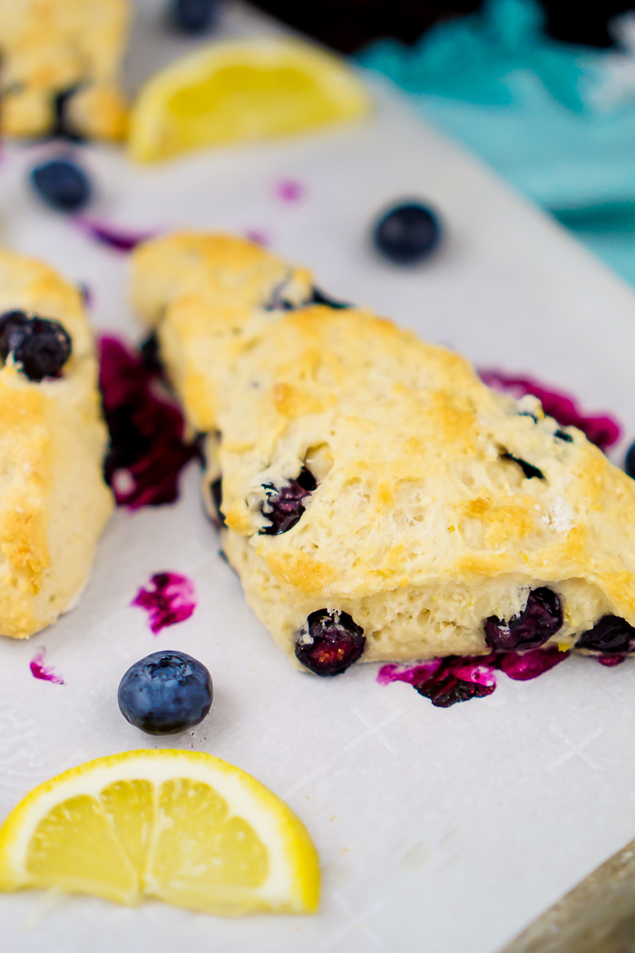 An close up photo or a lemon and blueberry scone showing some blueberries burst open into a really bright pink fushia color with the scone baked a nice golden yellow