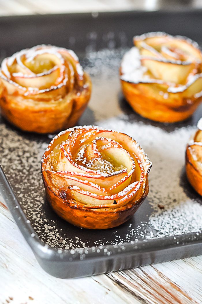 Sheet pan of apple roses sprinkled with powdered sugar makes a perfect apple dessert
