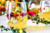 I'm dreaming of a White Christmas Sangria, filled with tasty red and green fruit for a festive holiday cocktail! Just fill up the sangria pitcher with red and green apples, pears, cranberries and pomegranates and some white wine and prosecco, too, of course! Lightly sweet and tangy fruit makes a Christmas Sangria Recipe your guests will love!