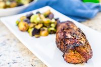 Garlic and Herb Pork Tenderloin with grilled potato and brussels sprouts side dish on white plate