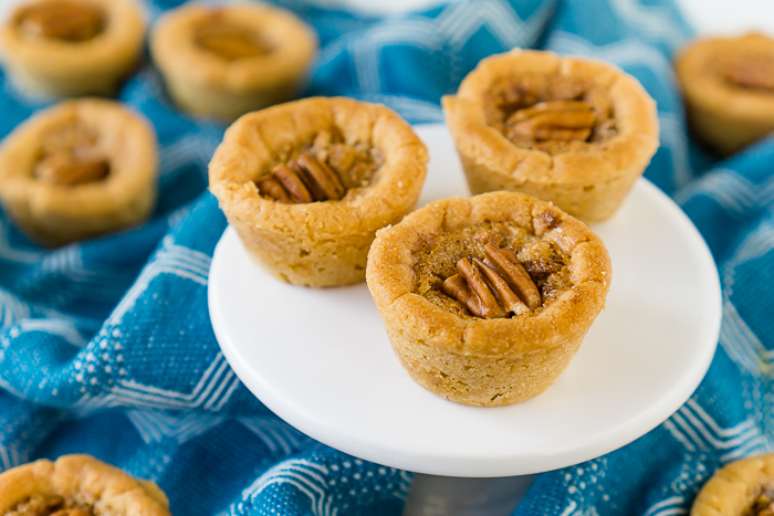 Delicious warm, brown sugar Pecan Pie filling in sweet sugar cookie cups makes the perfect Thanksgiving cookie - Pecan Pie Cookie Cups! Your family won't be able to stop eating this addicting fall dessert!  