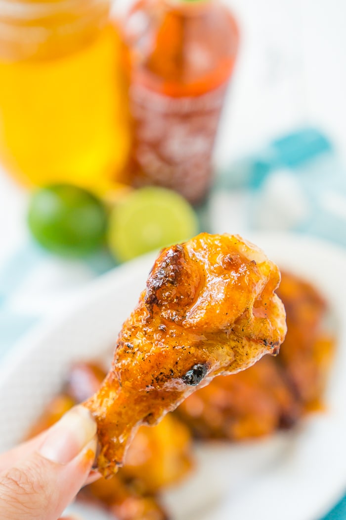 Up close photo of a chicken wing that is covered in a honey sriracha glaze. 