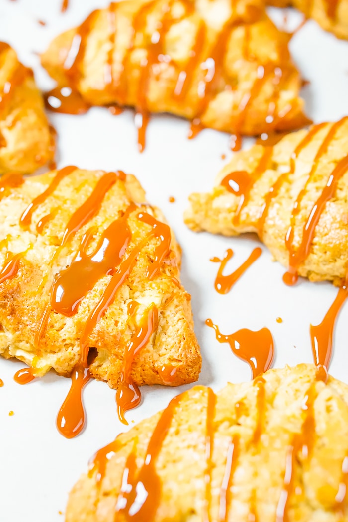 Up close shot of a caramel drizzle that has been added to golden brown scones that are apple flavored. 
